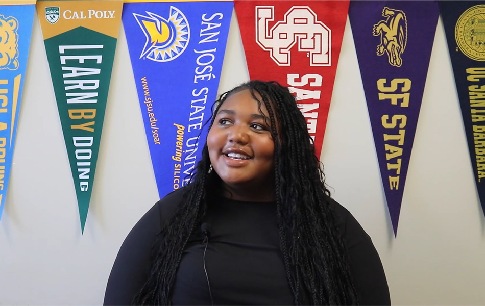 Eastside senior smiling in front of college banners